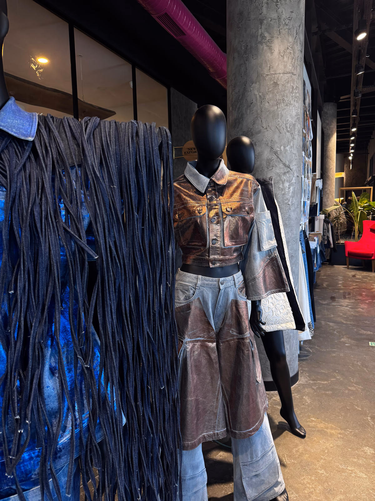 ALLDENIMS metallic denim look beside a fringed denim piece in the showroom